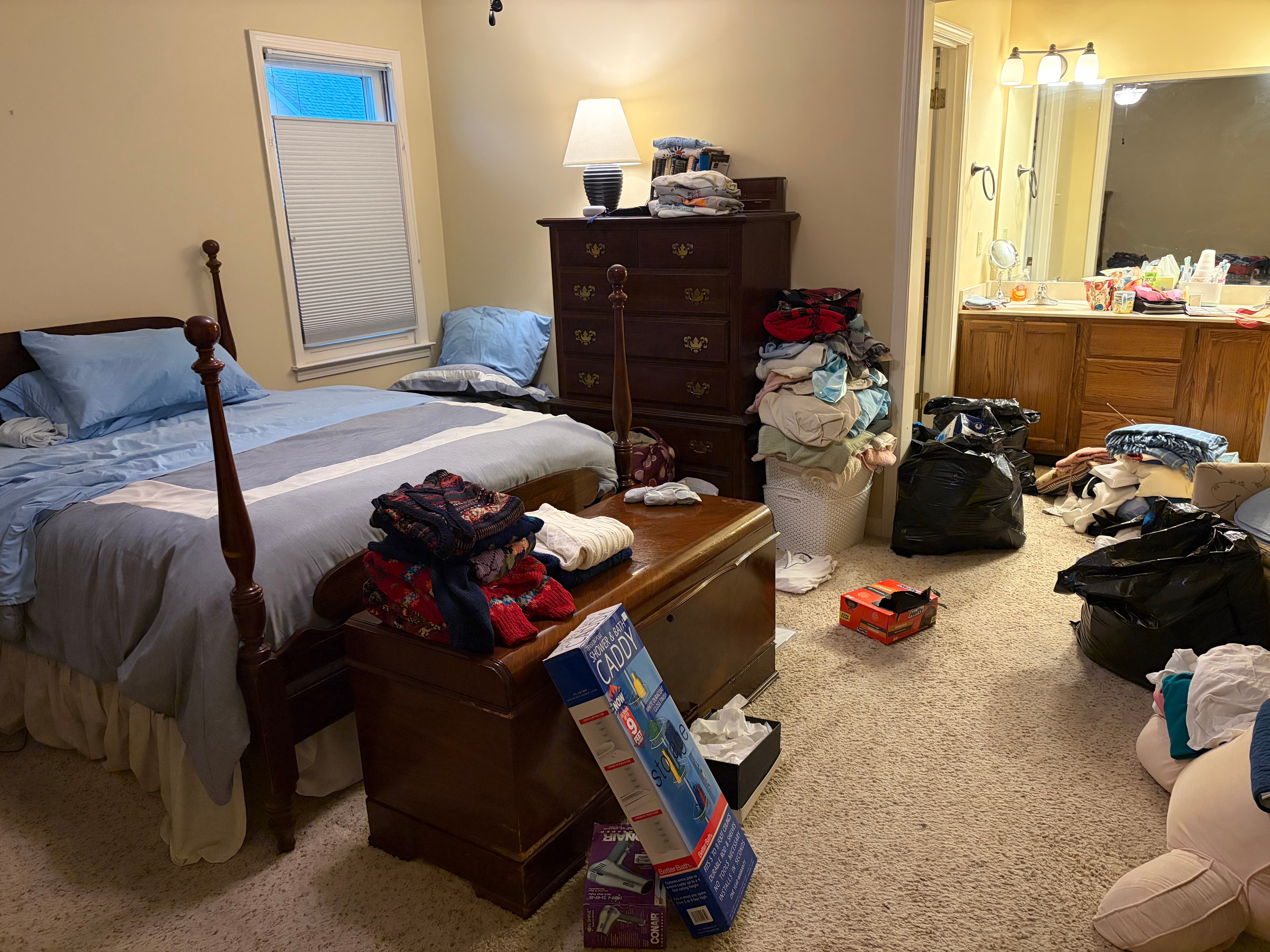 Bedroom before clearout — cluttered with clothes and boxes