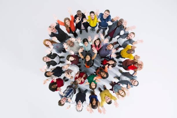 Diverse group of people standing in a circle, viewed from above, waving and smiling